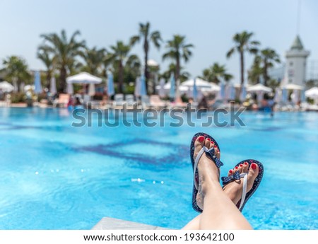Woman wearing flip-flops laying on the sunbed near the pool