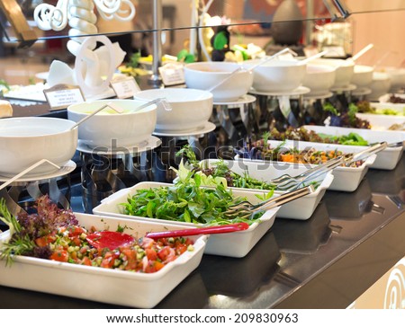 Assorted fresh salads displayed on a buffet in individual containers at a catered event or celebration, receding perspective