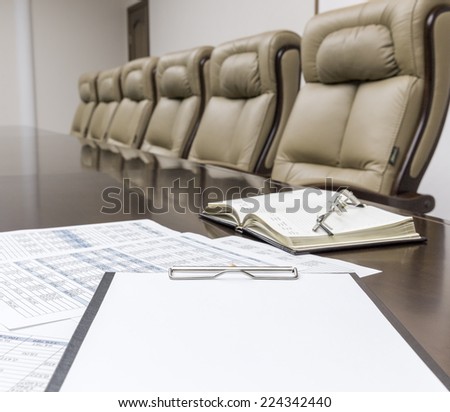 Closeup of empty clipboard on table in empty corporate conference room before business meeting in office