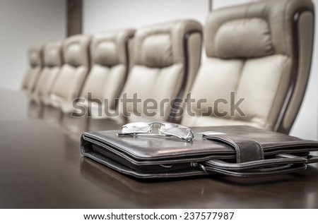 Closeup of briefcase on table in empty corporate conference room before business meeting in office