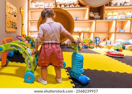 Similar – Image, Stock Photo Toddler playing with walker push toy; leaning on toy while standing and reaching for interactive button