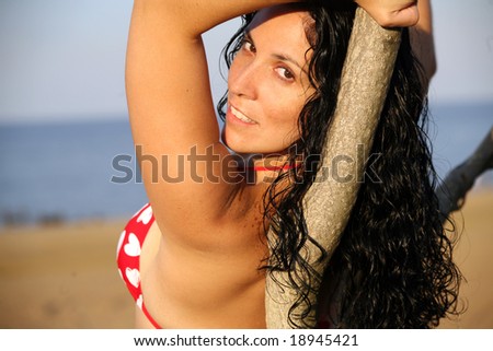 Girl in String Bikini Laying against tree at beach, looking at viewer