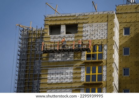 Workers sheathe the outer walls of a brick house with insulation. Insulation of the facade of the building. The concept of exterior decoration, moisture protection, sound insulation, energy saving. ストックフォト © 