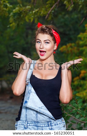 beautiful pin-up girl in denim overalls and a red bandana very surprised