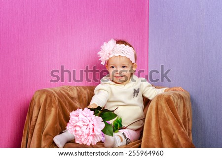 Little girl sitting in chair with a happy look on her face hold flowers shot in home interior