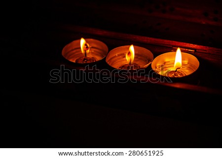 Three candles on a dark background in a warm light. The concept of the night before Christmas.