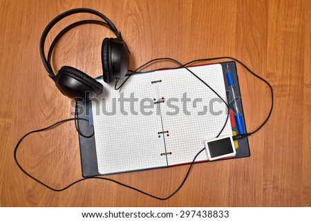Headphones and portable music player lie on notebook. Blank sheets of paper. Back to school.