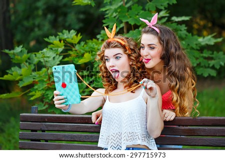 Best girlfriends do funny photos to your phone. Group selfies. Girls dressed in the style of Pin-up girl. Hipster. The girl shows tongue. The concept of true friendship.