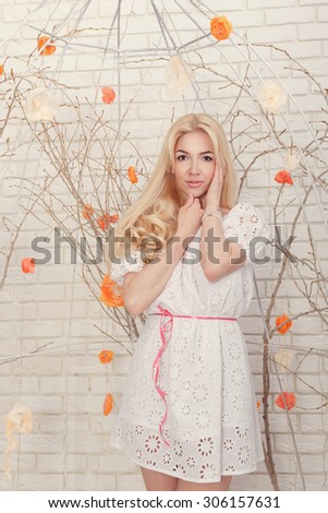 Cute blonde girl in home interior. Girl dressed in a white dress. The concept of home comfort.