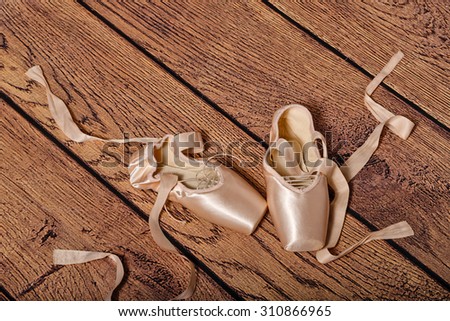 Ballet pointes lie on the wooden floor. Vintage. The concept of classical ballet and modern dance. Shot close-up.