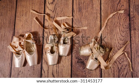 Evolution of ballet pointe: old and new, work. Ballet pointe shoes lie on the wooden floor. The concept of classical ballet and modern dance. Shot close-up.