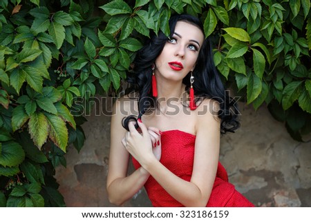 Attractive brunette girl in the red dress. The girl dreaming. Art Deco and Art Nouveau. The concept of retro fashion.