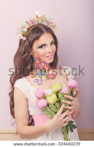 Young attractive girl with make-up floristry face art. A girl holding a bouquet of flowers. The concept of natural natural beauty.