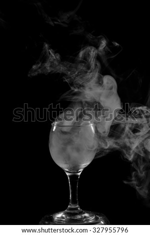 Abstract art. Hookah smoke into cocktail glass on a black background. Witch potion background for Halloween. Unusual bar drink. Drink in the glass with the effect of dry ice.