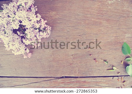 Romantic spring background - rustic wooden table with lilac flowers. Image filtered in faded, washed out, retro style; romantic vintage concept.