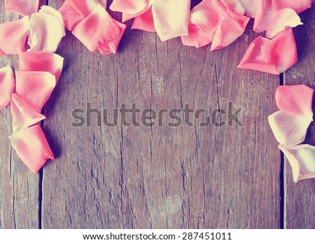 Romantic background - rustic wooden table with pink rose petals. Image filtered in faded, washed out, retro style; romantic, nostalgic vintage concept.