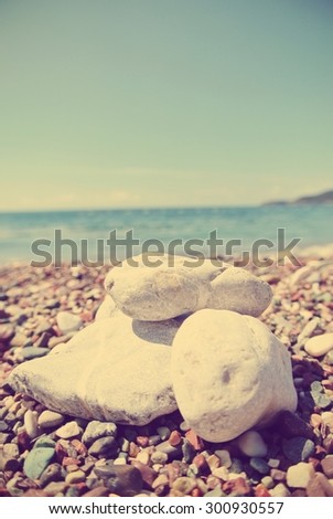 White pebbles on the beach, on a sunny summer day. Image edited in faded, washed out, retro, Instagram style with red filter and dark vignette; summer vintage concept.