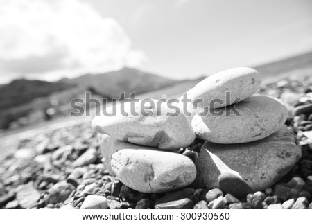 Closeup of white pebbles on the beach, on a sunny summer day, in black and white. Image filtered in faded, washed out, retro style; summer vintage concept. Tilted perspective.