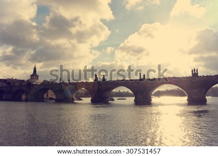 Charles' Bridge and the old town in Prague seen from the river, on a sunny day. Image filtered in faded, washed out, retro style with lens flare; nostalgic, vintage travel concept. Cityscape.