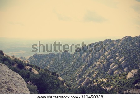 Strange rugged landscape of the Montserrat mountain, in Catalonia, Spain. Image filtered in faded, washed out, retro style with soft focus and dark vignette; nostalgic vintage travel concept.