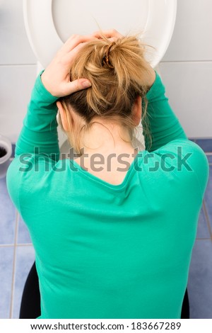 Woman bends over toilet to vomit