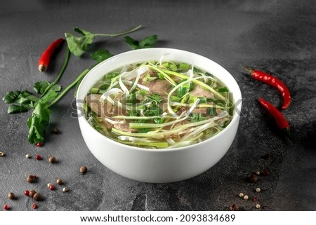 pho bo spicy broth or soup in white ceramic bowl with rice noodles, beef slices and herbs. concept of vietnamese food, side view Stok fotoğraf © 