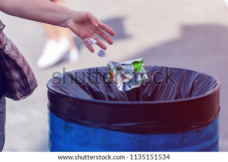 man throws garbage into a garbage can on the street Stockfoto © 