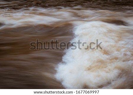 Waves and fast flowing muddy water in a river in a long-exposure creating a painterly effect Stok fotoğraf © 