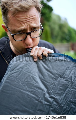 Close up of man with glasses blowing up a self inflatable sleeping pad for camping                               ストックフォト © 