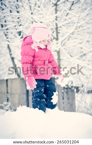 Portrait of a little girl in winter clothes having fun in the snow
