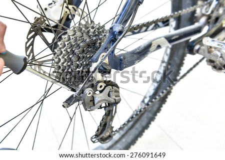 Serviceman hand repair bicycle whee with screwdriver. Bicycle gears and rear derailleur repair. A bicycle repairing. Mountain bike is repaired