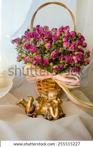 small basket with dried pink roses and angel figurine