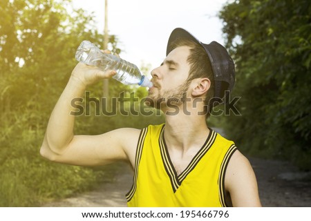 Sportsman drinking water from bottle after workout