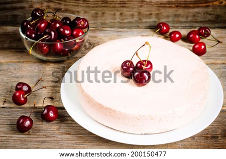chocolate-cherry cheesecake on a dark wood background. toning. selective focus on the cherry on top of the cheesecake