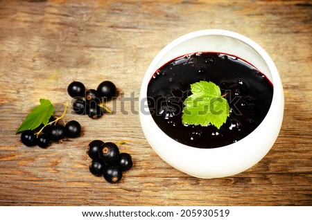 black currants jam in the white bowl on a dark wood background. toning selective focus on leave