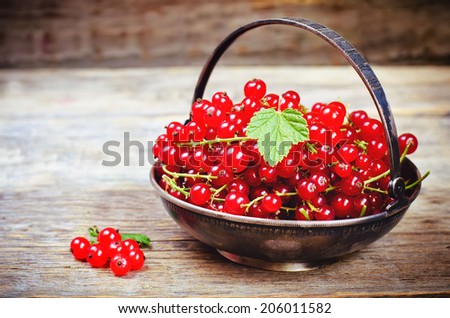 red currants on a dark wood background. toning. selective focus on leave
