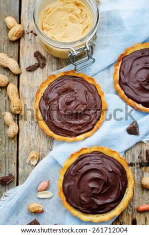 tartlets with peanut butter mousse and chocolate on a dark wood background. tinting. selective focus