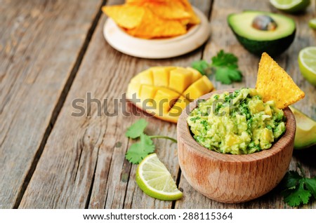 mango guacamole with corn chips on a dark wood background. the toning. selective focus
