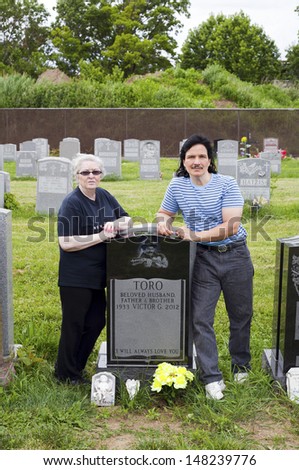 QUEENS, NEW YORK - JUNE 6: Sister Lydia and nephew Eddie visit grave of famed cuatro player Yomo Toro on the anniversary of his death.   Taken June 6, 2013 at Saint Michael's Cemetery in New York.