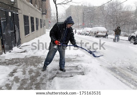 BRONX, NEW YORK - JANUARY 21: man shoveling during  a 6 to 10 inch snow storm and teen temperatures along Ogden avenue and 162nd street.  Taken January  21,  2014 in the Bronx,  New York.