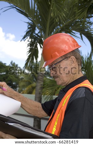 A senior looks at notes during the construction of a backyard.  Photographed in Bayamon Puerto Rico in December, 2009.  He was in his seventies at the time and of Puerto Rican ethnicity.