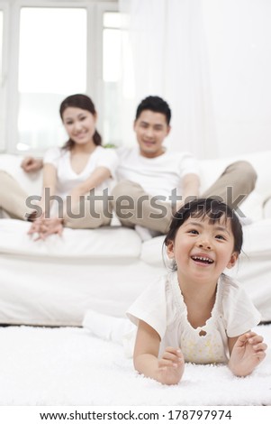 Young Chinese girl in a living room with parents in the background