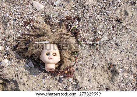 Head of children\'s doll thrown by the sea  on the beach trash