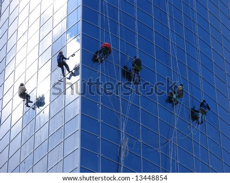 Six workers washing windows in the office building