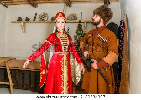 A young couple a man and a girl in Caucasian Circassian national costumes stand inside their traditional old house in the village Stock foto © 