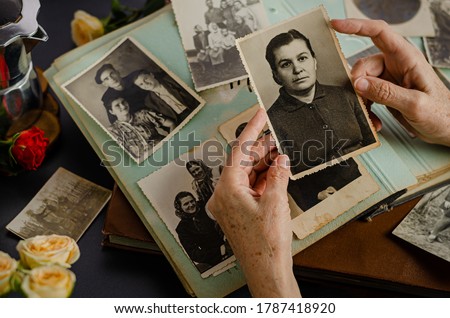 Female hands holding and old photo of her mother. Vintage photo album with photos. Family and life values concept.