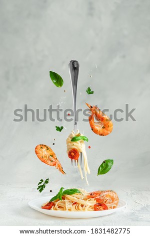 Pasta linguine with prawns and fork flying over the dish. Creative still life. Italian food.