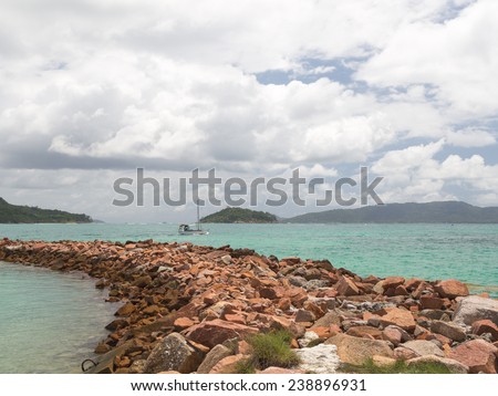 Praslin - November 3, 2014: Breakwater of the granite stones and the boat is sailing Praslin November 3, 2014, Praslin, Seychelles