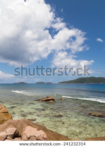 Vertical beautiful seascape with clear sea with small waves and the shore of granite stones, Seychelles