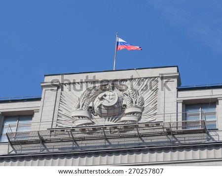 Moscow - April 12, 2015: The Russian flag flew over the building of the State Duma and the bas-relief emblem of the USSR against the blue sky on a clear day April 12, 2015, Moscow, Russia